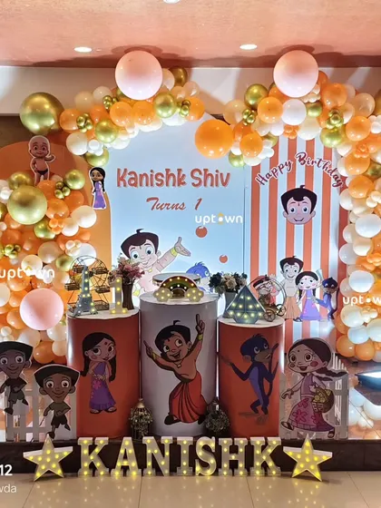 The full stage setup for the Chota Bheem party, with an orange and gold balloon arch.