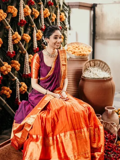A beautiful portrait of the bride in her half-saree, seated in a traditionally decorated space for a pre-wedding ritual.