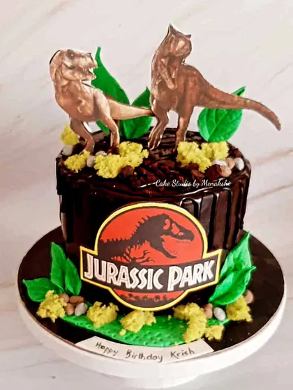 A thrilling Jurassic Park themed cake for a dinosaur lover. This chocolate drip cake is decorated with dinosaur figures and a jungle-like setting.
