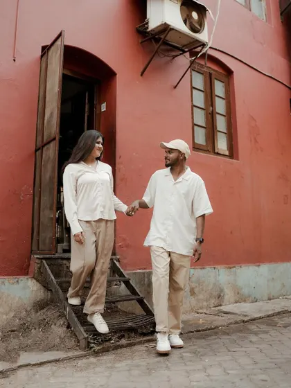 Hand in hand, the couple walks down a street lined with character, their coordinated outfits adding to the visual harmony of the shot.