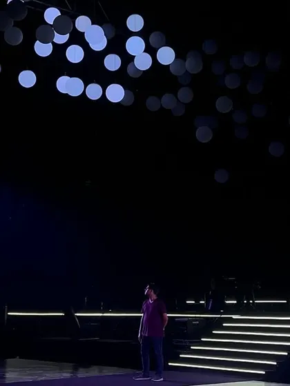A lone figure on the stage before the show begins, under a canopy of kinetic light balls, showcasing the scale of our high-tech productions.