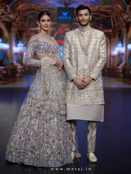 This runway couple showcases a gold multicolour bridal lehenga and a men's gold sherwani. The groom's outfit features exquisite floral multicolor embellishments, defining elegance at Bangalore Times Fashion Week.