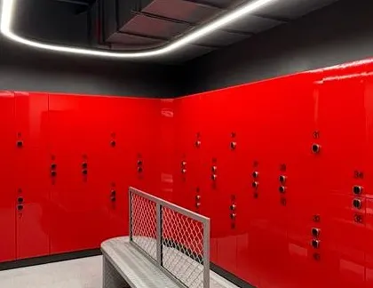 The locker room continues the gym's bold color scheme with high-gloss red lockers. The design is clean, functional, and efficient, providing a seamless experience for members before and after their workout.