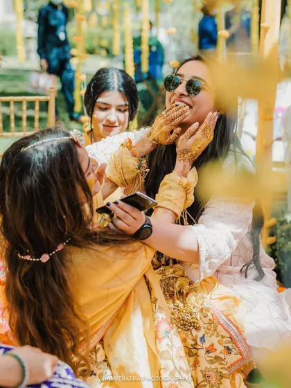 A fun, candid moment as friends playfully apply haldi to the bride.