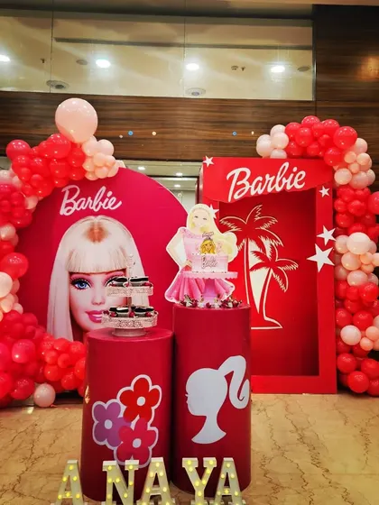 A fun and stylish Barbie-themed birthday party. This setup features a bold red backdrop, a Barbie silhouette, and a life-sized doll box prop for the perfect photo opportunity.