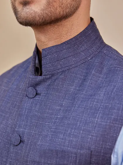 A close-up of the textured fabric and mandarin collar of the navy Nehru vest. The craftsmanship and detail are what give this classic piece its modern, refined edge.