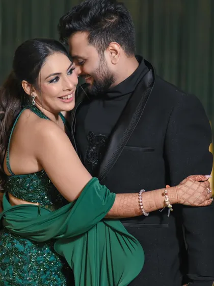 A candid moment of pure joy during a cocktail party. The couple's laughter and close embrace in their stylish green and black outfits show the fun and energetic side of their celebration.