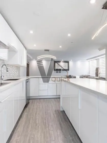 A look at a spacious and bright U-shaped kitchen. The all-white, handleless cabinetry and countertops create an ultra-clean and minimalist aesthetic, perfect for modern living.
