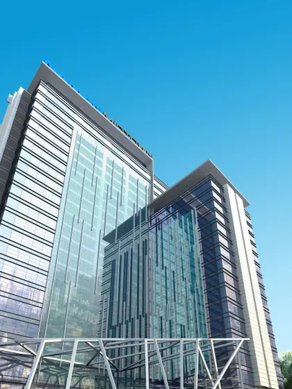 Looking up at the glass towers of Naman Midtown against a clear blue sky. This image captures the building's verticality and modern aesthetic, reflecting its status as an elite commercial address in Mumbai.