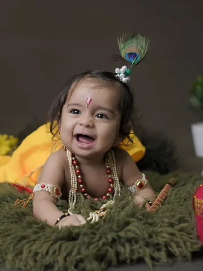 A classic pose for our Little Krishna theme, capturing a moment of pure happiness. The setup includes a pot of 'butter' and traditional jewelry for an authentic touch.