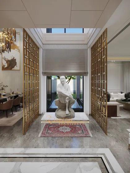 A central courtyard space featuring a serene sculpture, framed by golden jaali screens that separate it from the living and dining areas.