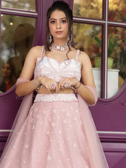 A front view of the pink bridesmaid lehenga, showing the delicate details of the blouse and choker.