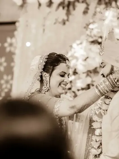 A sepia-toned photo of the Jaimala ceremony, focusing on the bride's joyful expression. This edit gives the moment a classic, timeless quality.