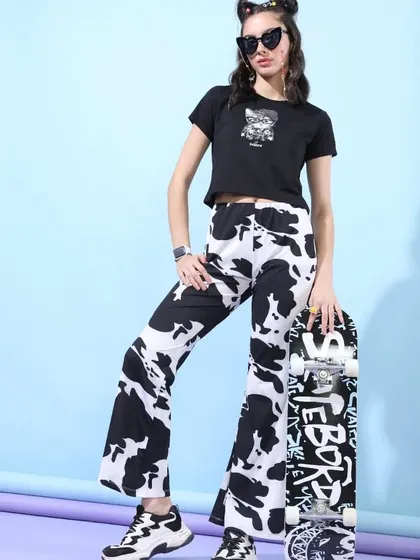 A bold, high-contrast look featuring cow-print pants and a black crop top, styled with a skateboard for an edgy, graphic appeal.