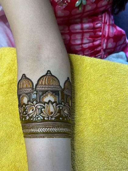 A close-up of a palace-themed arm band, showing the fine details in the architecture and lotus flowers.