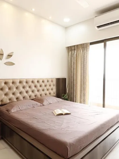 Another angle of the guest bedroom, showing the ample natural light from the large sliding glass door leading to the balcony. The neutral color palette makes the room feel bright and airy.