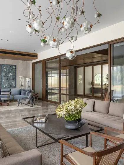 An expansive view of the K Residence living room, showing its two distinct seating areas. This design allows for both large gatherings and more intimate conversations, with large sliding glass doors connecting the space to the garden and flooding it with natural light.
