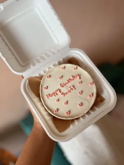 A minimalist bento cake with a simple "Happy Birthday" message and tiny piped hearts. It's a classic choice for any celebration.