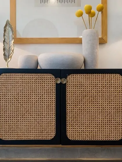 Cane furniture is making a comeback for good reason. This beautiful black and cane side cabinet adds texture, warmth, and a touch of timeless luxury to this living room.