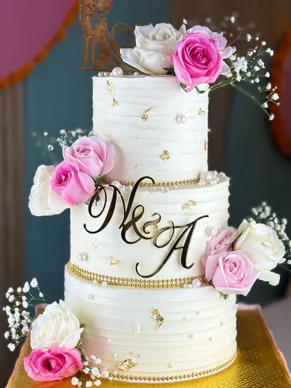 Pure elegance for your big day. Our best-selling white and pearl wedding cake, adorned with soft pink roses and delicate baby's breath, is the perfect blend of classic charm and modern romance.
