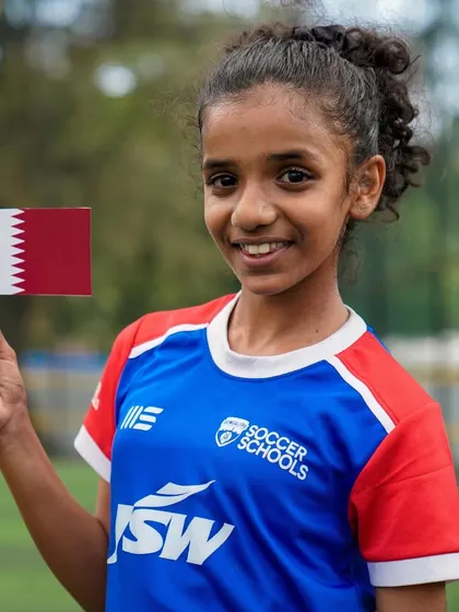A young girl proudly holds the flag of Qatar, excited about our international expansion. We are thrilled to bring our coaching philosophy to girls around the world.