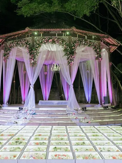 The stunning Sangeet stage with its illuminated glass floor and purple-lit drapes, ready for an evening of spectacular performances.