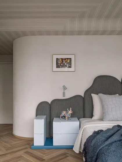 A detail shot of the master bedroom, focusing on the curved wall and custom headboard.