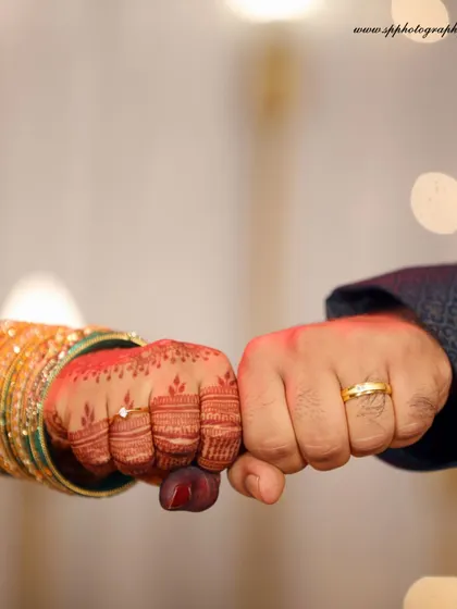 A playful fist bump between the couple, showing off their rings. It's a fun, modern take on the traditional ring photo that shows their personality.