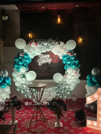 A beautiful and simple first birthday setup for a baby girl, using a teal and silver balloon ring with a neon sign and a light-up number.