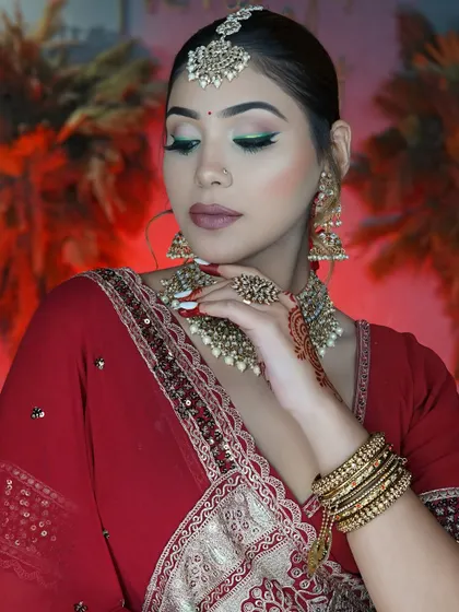 The quintessential Indian bride in classic red. This look combines a modern green winged liner with traditional red attire and gold jewelry for a timeless appeal.