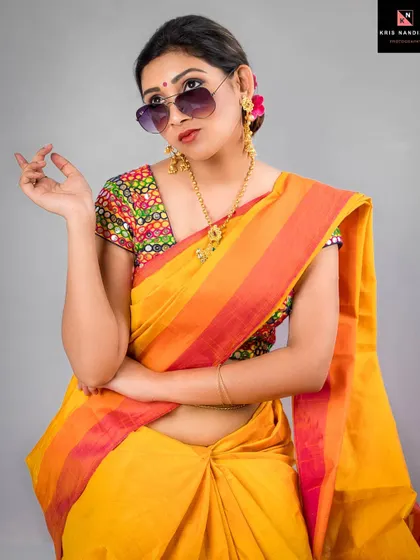 Capturing a moment of cheeky confidence, this portrait shows a model in a yellow saree and sunglasses. The pose and expression embody a modern, sarcastic take on traditional expectations.