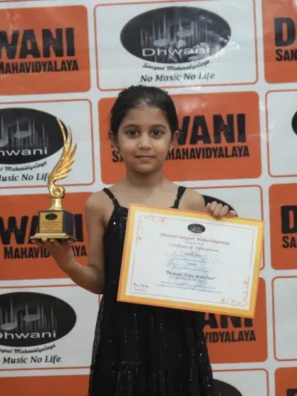 A young student proudly displays her certificate and trophy.