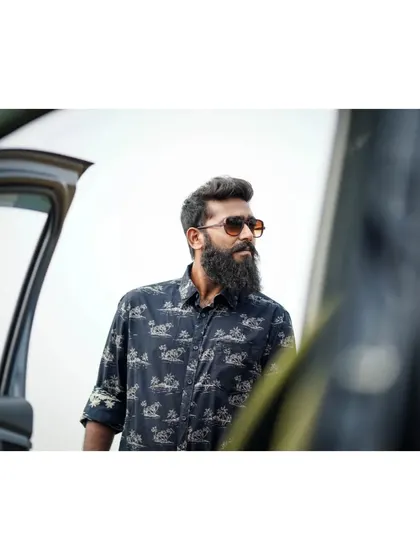 A candid-style shot of a man with a beard, framed by the door of a car. It feels spontaneous and cool.