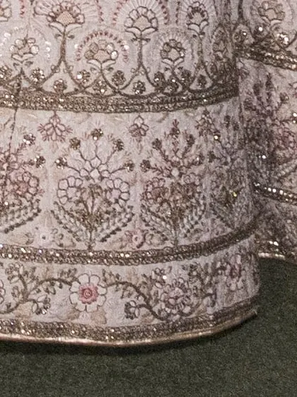 The border of the bridal lehenga skirt, featuring multiple layers of detailed floral and traditional motifs. This heavy work gives the outfit its grand appearance.