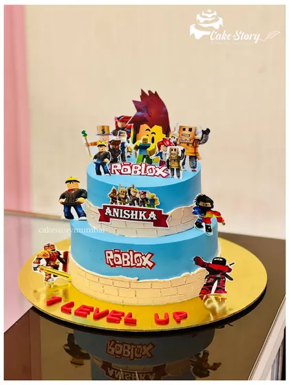 Level up! This two-tier Roblox themed cake is perfect for any gamer's birthday, decorated with logos and characters from the popular online game.