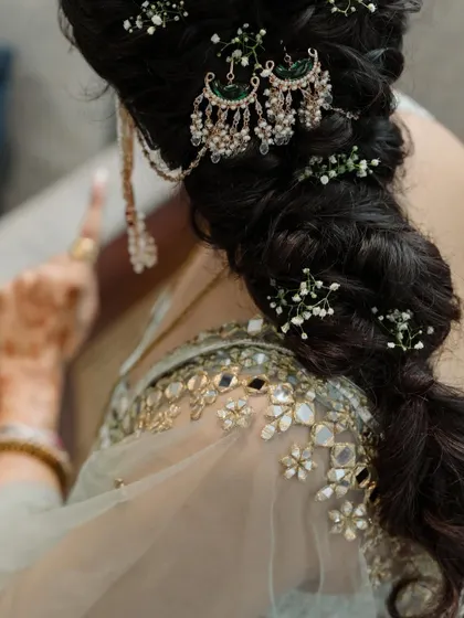 The art of bridal hairstyling. A close-up on the beautifully braided hair, adorned with baby's breath and a traditional passa, showcases the craftsmanship involved.