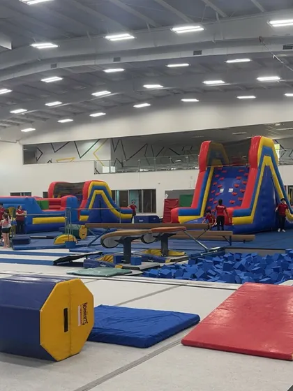 A look inside our gym during an Open House event. You can see our massive inflatable obstacle course set up alongside our gymnastics equipment, including the balance beam and foam pits. We love welcoming new faces to our facility.