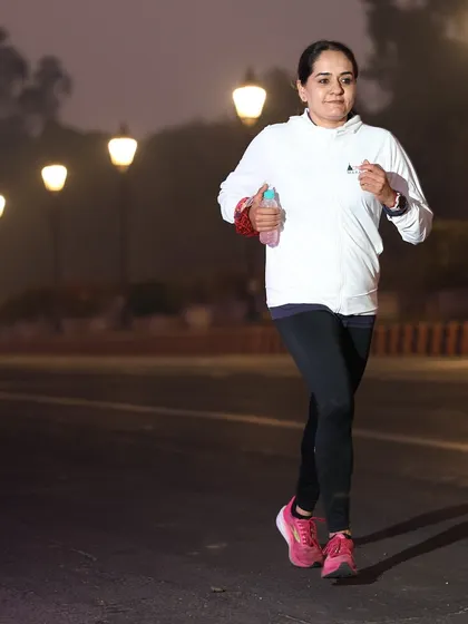 A female runner looking strong and focused during a night-time or early morning run.