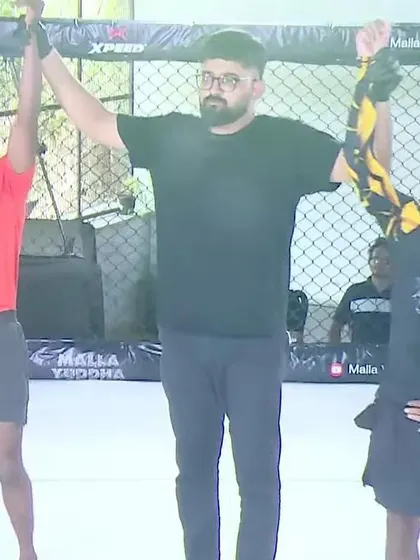 A referee raises the hand of our fighter after a hard fought victory. We train hard, and when we fight, we stand united as a team.
