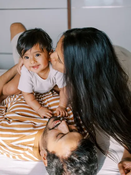 A family playing on the bed, the baby sleeping peacefully on his father's chest. A beautiful, serene moment.