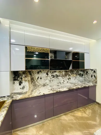 A luxurious kitchen with glossy purple base cabinets and white upper cabinets with gold-tinted glass. The dramatic granite countertop and backsplash tie the whole look together.
