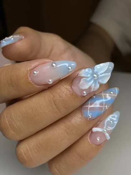 A side view of our intricate 3D nail art, highlighting the dimension of the sculpted bows and the delicate placement of each pearl bead on these long, stiletto-shaped nails.