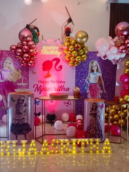 A glamorous Barbie themed party with two shimmer walls, Barbie doll cutouts, and a pink, gold, and chrome balloon arrangement.