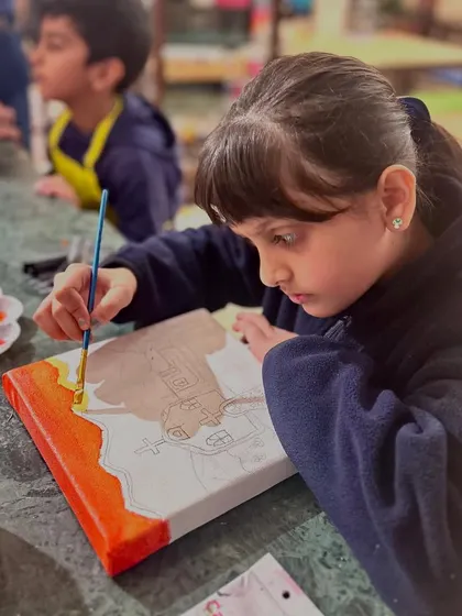 Another student carefully outlines her Mexican church design before starting to paint. This project teaches sketching, composition, and color blocking.
