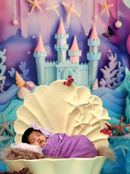 A wide view of our newborn mermaid session, showing the baby sleeping peacefully in a clamshell against the backdrop of an underwater castle.