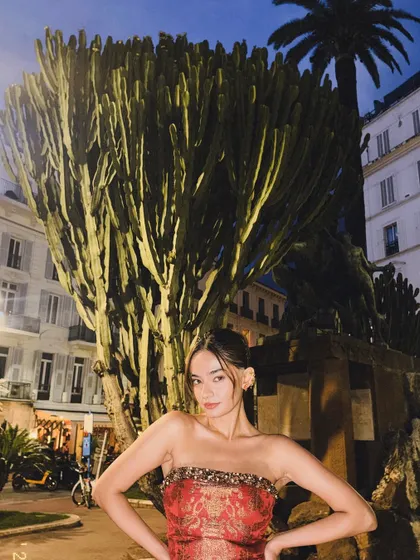 A fun shot of Anushka in her red dress, posing in front of a giant cactus in Cannes at night.