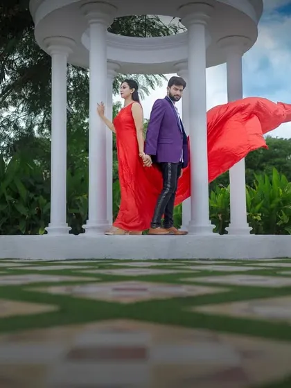 A creative and symmetrical shot at a white gazebo, with the red fabric adding a dynamic element of motion against the sky.