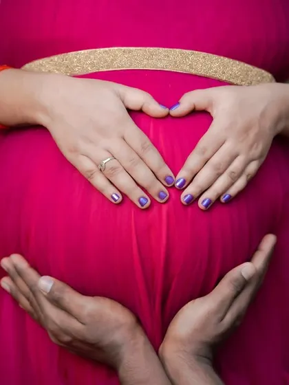 A close-up shot focusing on the hands of both parents forming a heart around the baby bump. This symbolic gesture is a beautiful way to represent their shared love and protection.