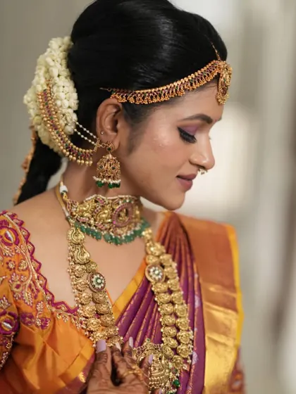 A side profile showcasing the beautiful hair accessories and layered necklaces. Every piece comes together to create a perfect bridal look.