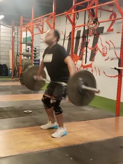 A dynamic shot of an athlete mid-pull during a hang snatch. This moment captures the explosive power generated from the hips to elevate the barbell.